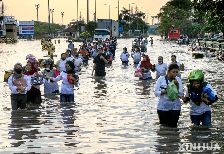[스마랑=신화/뉴시스] 20일(현지시간) 인도네시아 자바섬 스마랑 해안의 탄중 에마스 항구 마을에 만조로 인한 홍수가 발생해 주민들이 침수된 도로를 헤쳐 나가고 있다. 2022.06.21