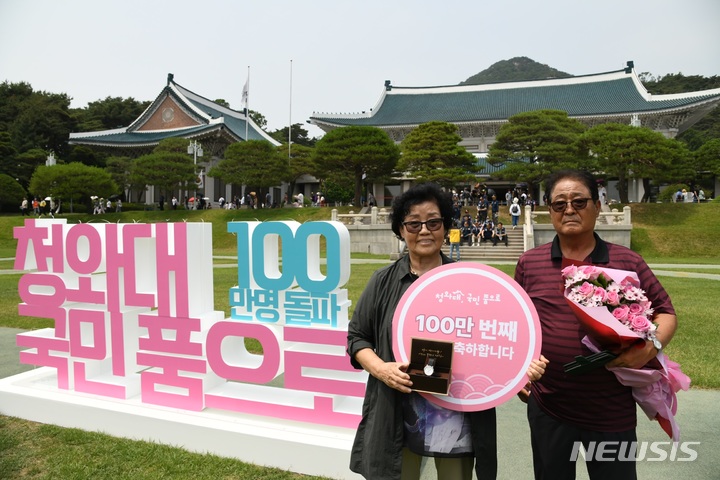 [서울=뉴시스] 문화재청이 청와대 개방 44일째인 22일 오후 청와대 대정원에서 개최한 '100만 번째 청와대 관람객' 기념행사에서 100만번째 관람객으로 선정된 김영순 씨가 기념품으로 받은 대통령 기념 시계와 꽃다발을 들고 기념촬영을 하고 있다. (사진=문화재청 제공) 2022.06.22. photo@newsis.com *재판매 및 DB 금지