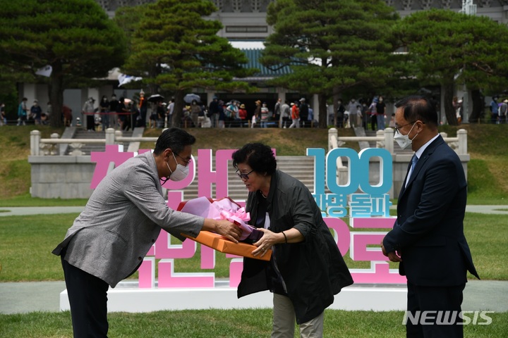 [서울=뉴시스] 문화재청이 청와대 개방 44일째인 22일 오후 청와대 대정원에서 개최한 '100만번째 청와대 관람객' 기념행사에서 청와대국민개방추진단 김명준 과장(왼쪽)이 주인공으로 선정된 김영순 씨에게 꽃다발과 기념품을 전달하고 있다. (사진=문화재청 제공) 2022.06.22. photo@newsis.com *재판매 및 DB 금지