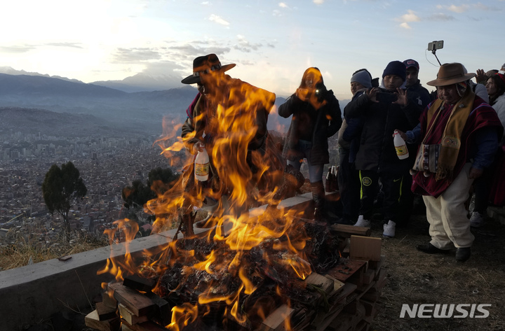 [엘알토=AP/뉴시스] 6월21일 볼리비아 고산 도시 엘 알토에서 안데스 종교 지도자가 새해 의식을 치르면서 모닥불에 술을 뿌리고 있다. 아이마라 원주민 공동체는 남반구의 동지를 맞아 '태양의 귀환'이라고 불리는 5530번째 안데스 새해를 기념한다. 2022.06.22.