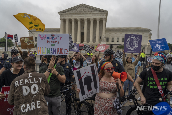 [워싱턴=AP/뉴시스] 23일(현지시간) 미 워싱턴DC 대법원 앞에서 자전거를 탄 경찰 통제선으로 나뉜 낙태권리 옹호 시위대와 반대 시위대가 시위하고 있다. 2022.06.24.
