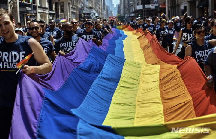 [뉴욕= AP/뉴시스] 뉴욕시의 26일 프라이드 행진에 참가한 성소수자(LTBGQ )와 시민들이 무지개빛 깃발을 들고 구호를 외치고 있다.  