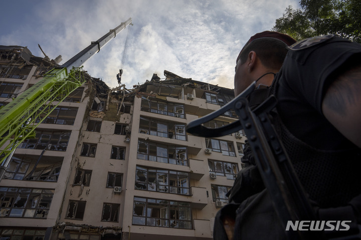 [키이우=AP/뉴시스] 우크라이나 군인이 26일(현지시간) 러시아군의 미사일 공격으로 파괴된 주택 건물을 올려다 보고 있다. 2022.06.26.