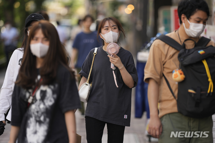 [도쿄=AP/뉴시스]27일 일본 도쿄에서 한 시민이 더위를 식히기 위해 휴대용 선풍기를 사용하고 있다. 이날 도쿄도 네리마구에서는 36.4도의 폭염이 관측됐다. 2022.06.27.