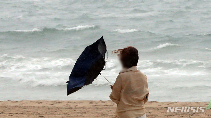 [부산=뉴시스] 지난 29일 해운대해수욕장을 찾은 시민이 힘겹게 우산을 쓴 채 걸어가고 있다. 2022.06.29. yulnetphoto@newsis.com