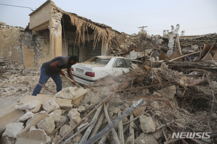[사예 호쉬=AP/뉴시스]이란 수도 테헤란 남쪽으로 약 1000km 떨어진 호르모즈칸 지방 사예 호쉬 마을에서 2일(현지시간) 한 남성이 지진으로 부서진 건물잔해를 치우고 있다. 