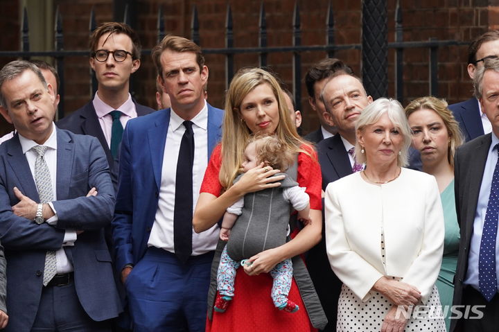[런던=AP/뉴시스] 7일(현지시간) 보리스 존슨 영국 총리가  영국 런던 다우닝가 10번지 총리관저 앞에서 사임 기자회견을 하고 있는 것을 그의 부인 캐리 존슨 여사(가운데)가 딸 로미를 안고 지켜보고 있다. 2022.07.07.