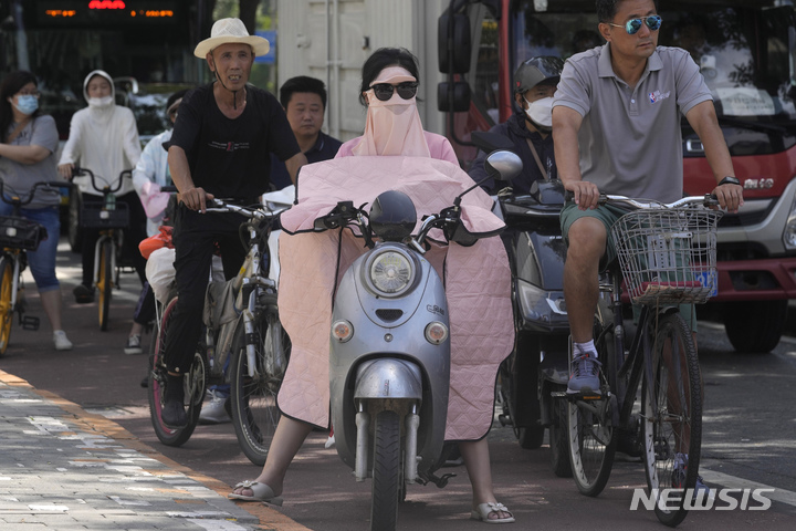 [베이징=AP/뉴시스] 13일 중국 베이징 도심에서 선글라스, 마스크와 천으로 온몸을 가린 한 여성이 오토바이를 타고 신호를 기다리고 있다. 2022.07.14 