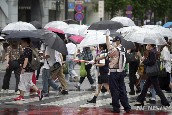 [도쿄=AP/뉴시스]지난 14일 일본 도쿄 시부야에서 마스크를 착용한 시민들이 우산을 쓰고 횡단보도를 건너고 있다. 2022.07.22.