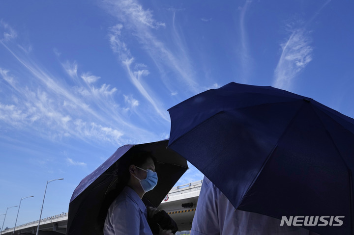[베이징=AP/뉴시스] 더위를 피해 우산을 쓰고 있는 베이징 시민. 2022.07.20
