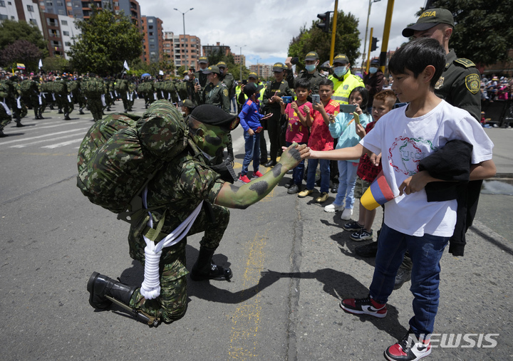 [보고타=AP/뉴시스] 20일(현지시간) 콜롬비아 수도 보고타에서 제212주년 콜롬비아 독립 기념일을 맞아 열린 퍼레이드에 참석한 한 군인이 구경나온 한 소년과 인사하고 있다. 2022.07.21.