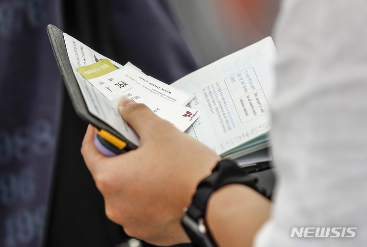 [서울=뉴시스] 공항에서 한 시민이 비행기표와 여권을 들고 줄 서 있다. (사진= 뉴시스 DB) photo@newsis.com