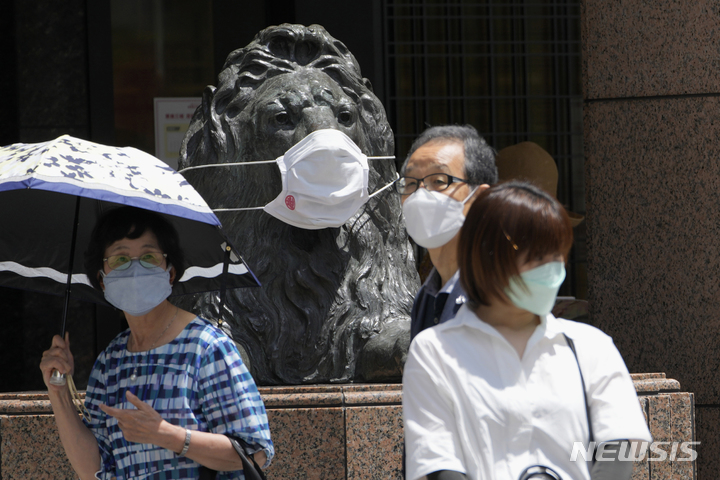 [도쿄=AP/뉴시스]지난달 28일 일본 도쿄 긴자 쇼핑 지역 일대에서 마스크를 쓰고 있는 한 백화점의 랜드마크 사자 동상 앞을 코로나 확산을 억제하기 위해 마스크를 쓴 사람들이 걷고 있다. 2022.08.23.