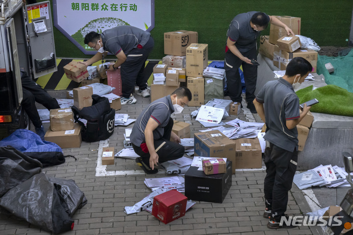 [베이징=AP/뉴시스]마스크를 쓴 중국의 택배 기사들이 29일 베이징의 거리에서 택배 상자들을 분류하고 있다. 2022.07.29