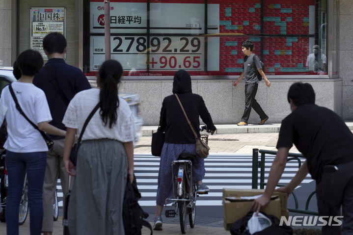 [도쿄=AP/뉴시스] 일본 수도 도쿄 시내 증시 전광판 앞에 있는 횡단보도에서 시민들이 신호를 기다리고 있다. 2022.08.17.