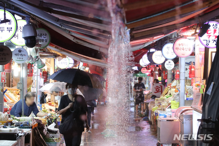 [서울=뉴시스] 권창회 기자 = 비가 내리고 있는 8일 오후 서울 강동구 둔촌역 전통시장에서 시민들이 우산을 쓰고 이동하고 있다. 2022.08.08. kch0523@newsis.com