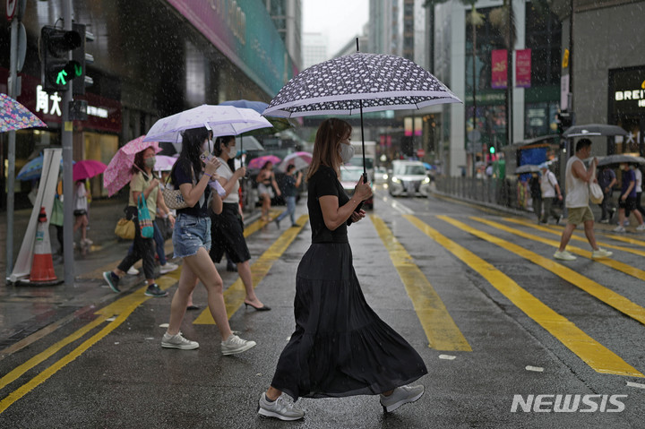 [홍콩=AP/뉴시스] 태풍 경보가 내린 홍콩 시내에서 9일 코로나 예방을 위해 마스크를 착용한 시민들이 횡단보도를 건너고 있다. 2022.08.10 