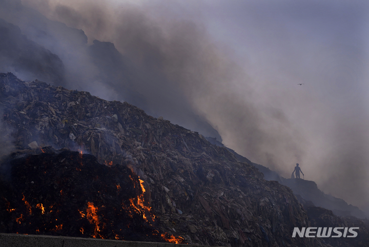 [AP/뉴시스] 4월27일 인도 뉴델리의 발스와 쓰레기 매립지에서 불이 난 와중에 한 사람이 쓰레기더미를 뒤지고 있다