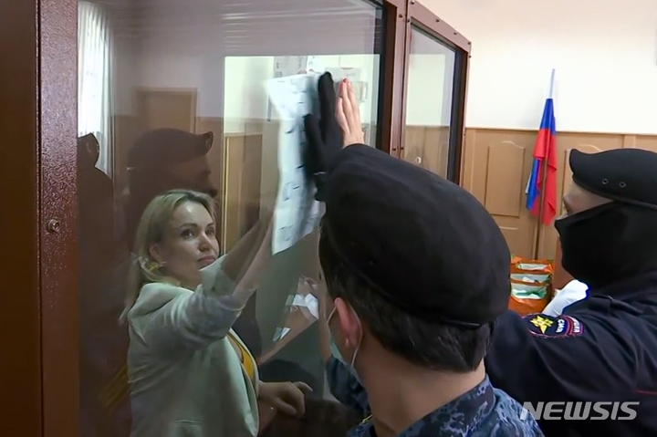 [모스크바=AP/뉴시스] 러시아 국영방송 생방송 뉴스 중 반전시위를 벌였던 마리아 오브샤니코바가 11일(현지시간) 모스크바에서의 법정 공판에 앞서 "살해당한 아이들이 당신들 꿈에 나올 것"이라고 쓰인 종이를 들어 보이는 동안 경찰이 이를 손으로 가리고 있다. 러시아 법원은 허위사실 유포 혐의로 수사와 재판이 진행 중인 오브샤니코바에게 약 두 달간의 가택연금 처분을 내렸다. 2022.08.12.