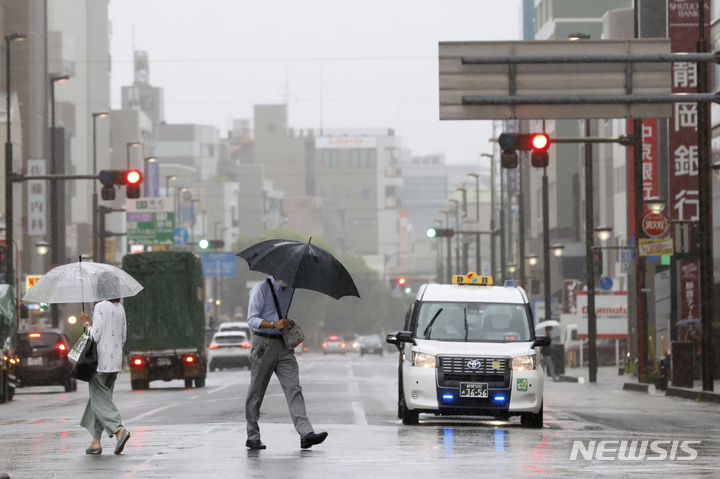 [시즈오카=AP/뉴시스]지난 13일 일본 시즈오카에 비가 몰아치면서 시민들이 우산을 꼭 잡고 길을 건너고 있다. 이날은 태풍 메아리가 도쿄를 향해 하며 폭우가 쏟아졌다. 2022.08.18.
