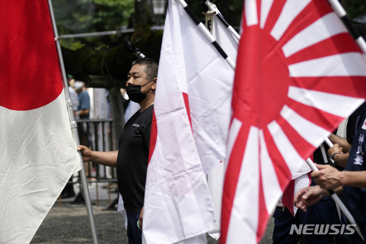 [도쿄(일본)=AP/뉴시스]일본의 패전일인 지난 15일 야스쿠니 신사를 방문한 시민들이 일장기(왼쪽)와 욱일기를 들고 있다. 태평양 전쟁 A급 전범이 합사된 야스쿠니 신사는 일본 군국주의의 상징이다. 2022.08.17.