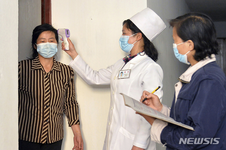 [평양=AP/뉴시스]조선중앙통신이 제공한 사진. 한 의사가 북한 평양에서 코로나19 확산을 방지하기 위해 거주자의 체온을 확인하고 있다. 2022.09.28