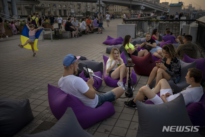 [키이우=AP/뉴시스] 28일(현지시간) 우크라이나 키이우에서 시민들이 물담배를 피우며 해지는 시내 거리에 앉아 있다. 2022.08.29.