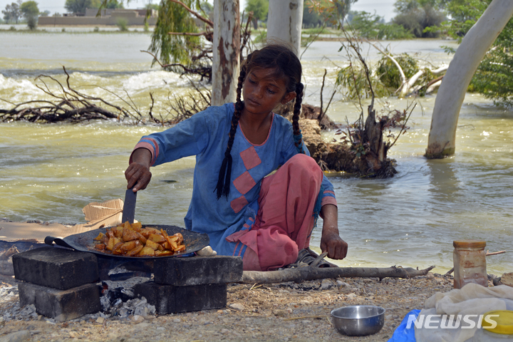 [물탄=AP/뉴시스] 8월 31일(현지시간) 파키스탄 펀자브주 물탄에서 한 소녀가 범람한 물가에 앉아 감자를 요리하고 있다. 파키스탄 '최악의 홍수'로 1100명 이상이 숨지고 국토 3분의 1이 침수된 가운데 현지 당국은 콜레라 등 수인성 질병 확산을 우려하고 있다. 2022.09.01.