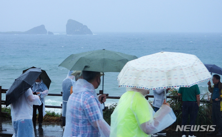 [서귀포=뉴시스] 우장호 기자 = 제주 서귀포시 대정읍 송악산에 우산을 쓴 관광객들이 걸어가고 있다. 뉴시스DB woo1223@newsis.com