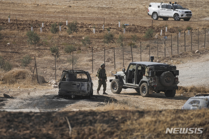 [요르단강 서안지구=AP/뉴시스]이스라엘 군인이 4일(현지시간) 요르단강 서안지구에서 버스 총격 사건이 발생한 현장 부근에 팔레스타인 무장 괴한들이 이용한 것으로 알려진 불에 탄 차량 옆을 지나가고 있다. 2022.09.04.