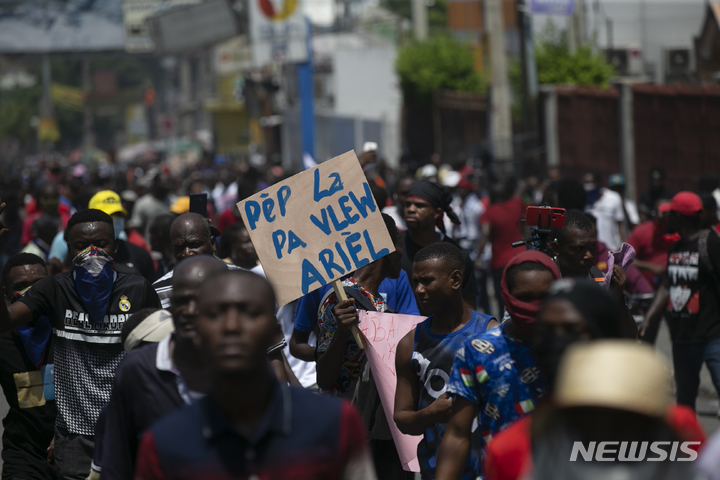 [포르토프랭스( 아이티)=AP/뉴시스] 앙리 총리 퇴진을 요구하는 팻말을 든 아이티 시위대가 7일(현지시간) 수도 포르토 프랭스 시내를 행진하고 있다.   