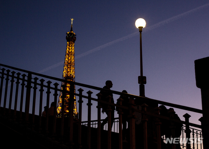 [파리=AP/뉴시스] 안 이달고 프랑스 파리 시장은 13일(현지시간) 기자회견을 통해 러시아발 에너지 위기 심화로 파리의 상징인 에펠탑 조명을 약 1시간 일찍 끈다고 밝혔다. 이에 따라 새벽 1시까지 조명이 들어오던 에펠탑은 오후 11시 45분에 소등하게 된다. 사진은 지난 2월 9일 시민들이 에펠탑 옆 다리를 걷는 모습. 2022.09.14.