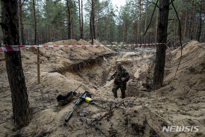 [이지움=AP/뉴시스] 우크라이나 군인들이 15일(현지시간) 우크라이나 하르키우주 이지움에서 발견된 집단매장 묘지를 살펴보고 있다. 2022.09.16.