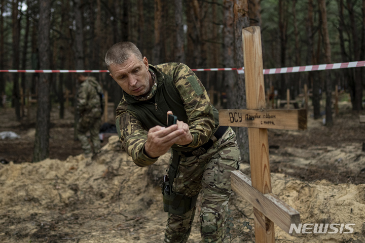 [이지움=AP/뉴시스] 우크라이나 군인들이 15일(현지시간) 우크라이나 하르키우주 이지움에서 발견된 집단매장 묘지를 살펴보고 있다. 2022.09.16.