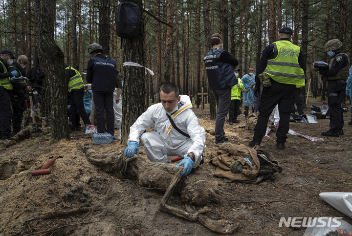 [이지움(우크라이나)=AP/뉴시스] 16일(현지시간) 우크라이나 하르키우주 이지움의 시신 440구가 묻힌 집단 매장지에서 조사관들이 시신 발굴 및 조사 작업을 벌이고 있다. 2022.09.17
