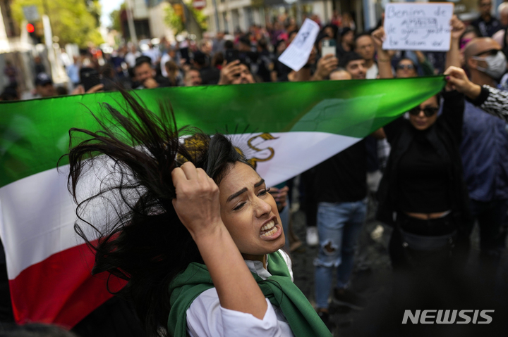 [이란=AP/뉴시스] 21일(현지시간) 튀르키예 이스탄불 이란 총영사관 밖에서 마하 아미니의 죽음에 항의하는 시위에 한 여성이 이란 국기 옆에서 구호를 외치고 있다. 2022.09.23.