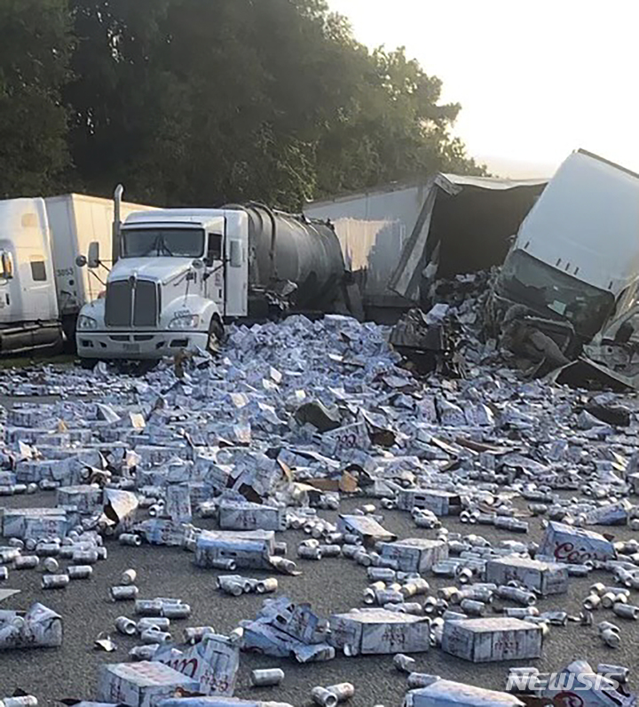 [브룩스빌(미 플로리다주)=AP/뉴시스]맥주 수천 상자를 가득 실은 세미 트레일러 한 대가 충돌 사고를 내면서 전복돼 쏟아진 맥주 캔들이 21일(현지시간) 미 플로리다주 브룩스빌 인근 75번 주간 고속도로를 뒤덮고 있다. 이 사고로 고속도로가 일시적으로 폐쇄됐다. 2022.9.22