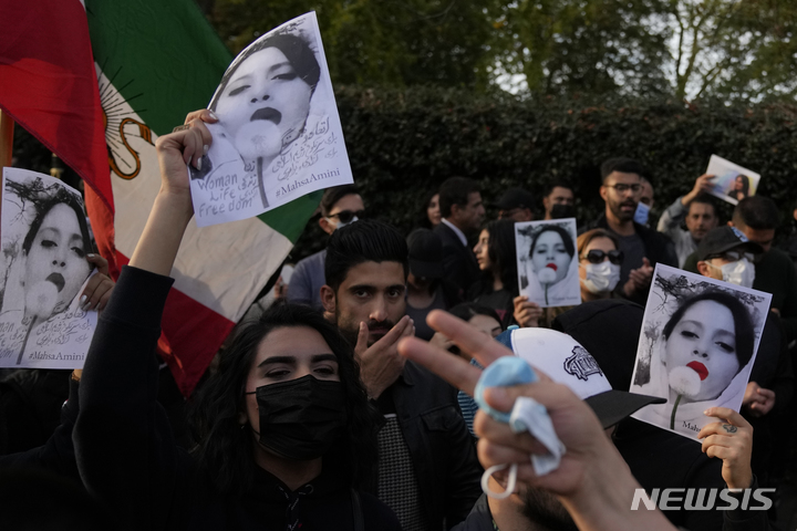 [런던=AP/뉴시스]시위대가 25일(현지시간) 영국 런던의 이란 대사관 밖에서 이란 여성 마흐사 아미니의 사진을 들고 있다. 이들은 아미니가 이란의 엄격한 복장 규정을 위반한 혐의로 종교 경찰에 체포된 데 항의하는 시위를 벌이고 있다. 2022.09.27
