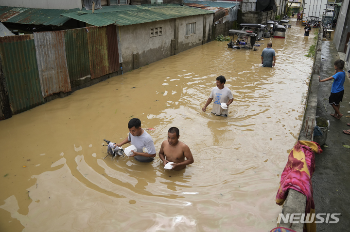 [불라칸=AP/뉴시스] 26일(현지시간) 필리핀 불라칸주 산미구엘에서 주민들이 먹을거리를 들고 태풍 '노루'로 침수된 도로를 헤엄쳐 나가고 있다. 2022.09.27. 