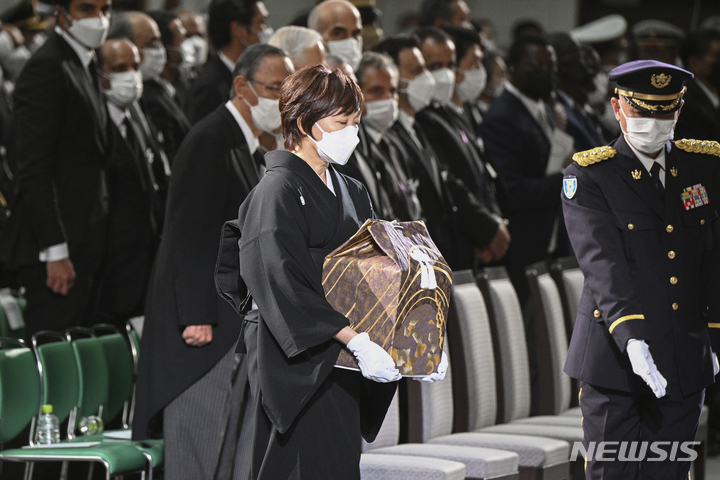 [도쿄=AP/뉴시스]27일 아베 신조 전 총리의 국장이 도쿄 니혼부도칸에서 열리고 있다. 아베 전 총리의 부인 아키에 여사가 그의 유골을 들고 앞으로 걸어가고 있다. 2022.09.27.