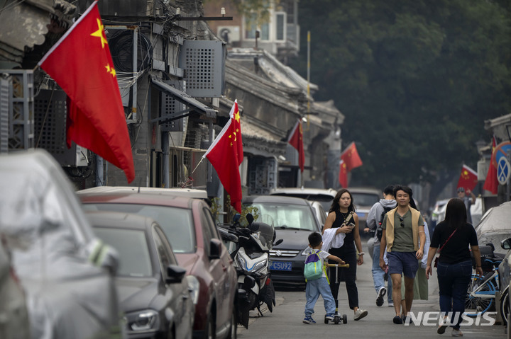 [베이징=AP/뉴시스] 사람들이 국경절 연휴기간 첫 날인 1일 베이징에서 오성홍기가 걸린 골목을 따라 걷고 있다. 2022.10.04