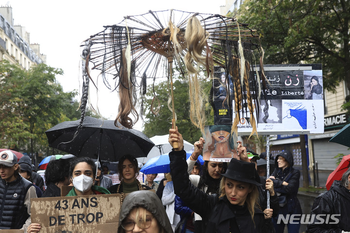 [파리=AP/뉴시스] 시위대가 2일(현지시간) 프랑스 파리에서 이란 경찰에 구금되던 중 사망한 젊은 여성을 추모하는 시위자들에 연대하기 위해 가짜 머리카락이 달린 우산을 들고있다. 2022.10.06.