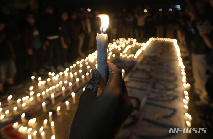 [베카시(인도네시아)=AP/뉴시스] 한 남성이 3일(현지시간) 인도네시아 베카시에서 경기장에서 사망한 아레마 FC 팬들을 위한 촛불시위에 참석해 촛불을 들고 있다. 2022.10.05.