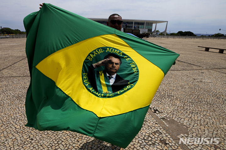 [브라질=AP/뉴시스] 재선에 출마하는 보우소나루 대통령 지지자가 선거 다음날인 3일(현지시간) 브라질리아 플라날토 대통령궁 밖에서 2차선거가 시작되는 날 깃발을 흔들고 있다. 2차 선거는 오는 30일 열린다. 2022.10.04. 