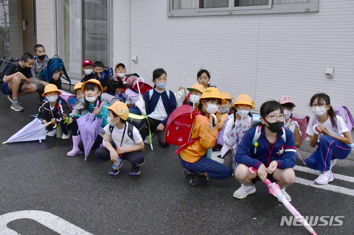 [미사와=AP/뉴시스]일본 정부는 13일 북한의 탄도미사일 발사 징후를 포착해 전국순시경보시스템(J-ALERT)을 발신했다가 취소했다. 자료사진은 2022년 10월4일 일본 북부 아오모리현 미사와시에서 초등학생들이 북한의 미사일 발사 보도 직후 등교길에 건물 근처에서 피난처를 찾고 있는 모습. 2023.04.13.