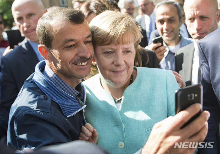 [베를린=AP/뉴시스] 2015년 9월 9일, 메르켈 전 독일 총리는 베를린의 한 난민 시설에서 난민과 사진을 찍고 있다. 2022.10.05.