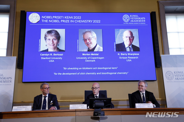 [AP/뉴시스] 5일 스웨덴 과학원이 노벨 화학상 수상자를 발표하는 가운데 공동 수상자인 베르토지, 멜달 및 샤프리스 박사 모습이 스크린에 떠있다