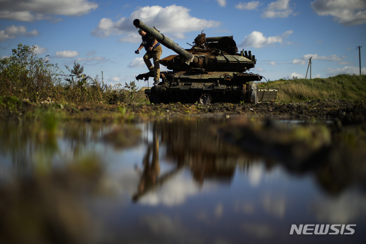 [치스토보디우카=AP/뉴시스] 6일(현지시간) 우크라이나 치스토보디우카 마을에서 우크라이나 군인이 파괴된 러시아 전차에서 뛰어내리는 모습이 물에 비치고 있다. 2022.10.07.