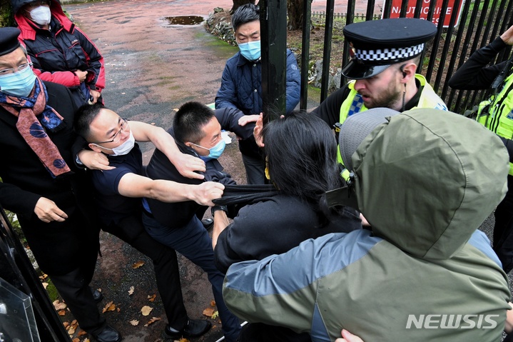 [맨체스터=AP/뉴시스] 지난 10월16일(현지시간) 영국 맨체스터의 중국 영사관 앞에서 반중 시위를 벌이던 홍콩 이주민 보브 챈(가운데 노란 마스크)이 자신을 영사관으로 끌고 들어가려는 직원들에게 저항하고 있다. 