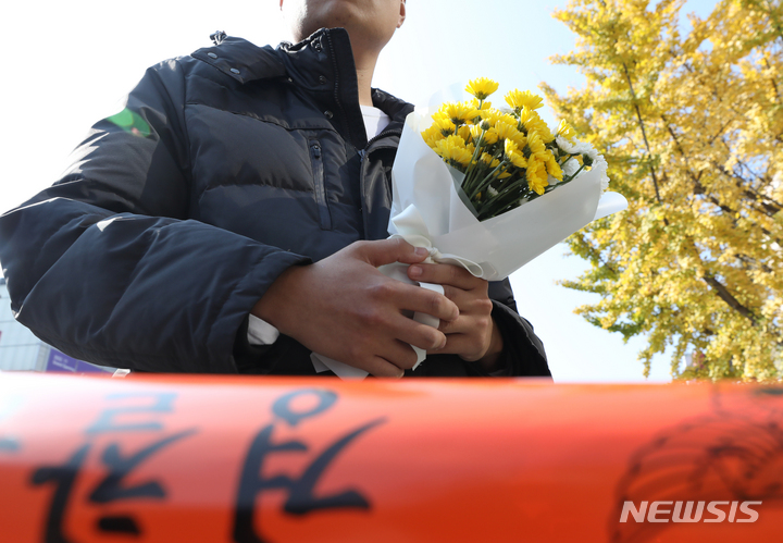 [서울=뉴시스] 김금보 기자 = 30일 오후 서울 용산구 이태원 압사 사고 현장에서 한 시민이 근조화를 들고 추모 공간 마련을 기다리고 있다. 2022.10.30. kgb@newsis.com